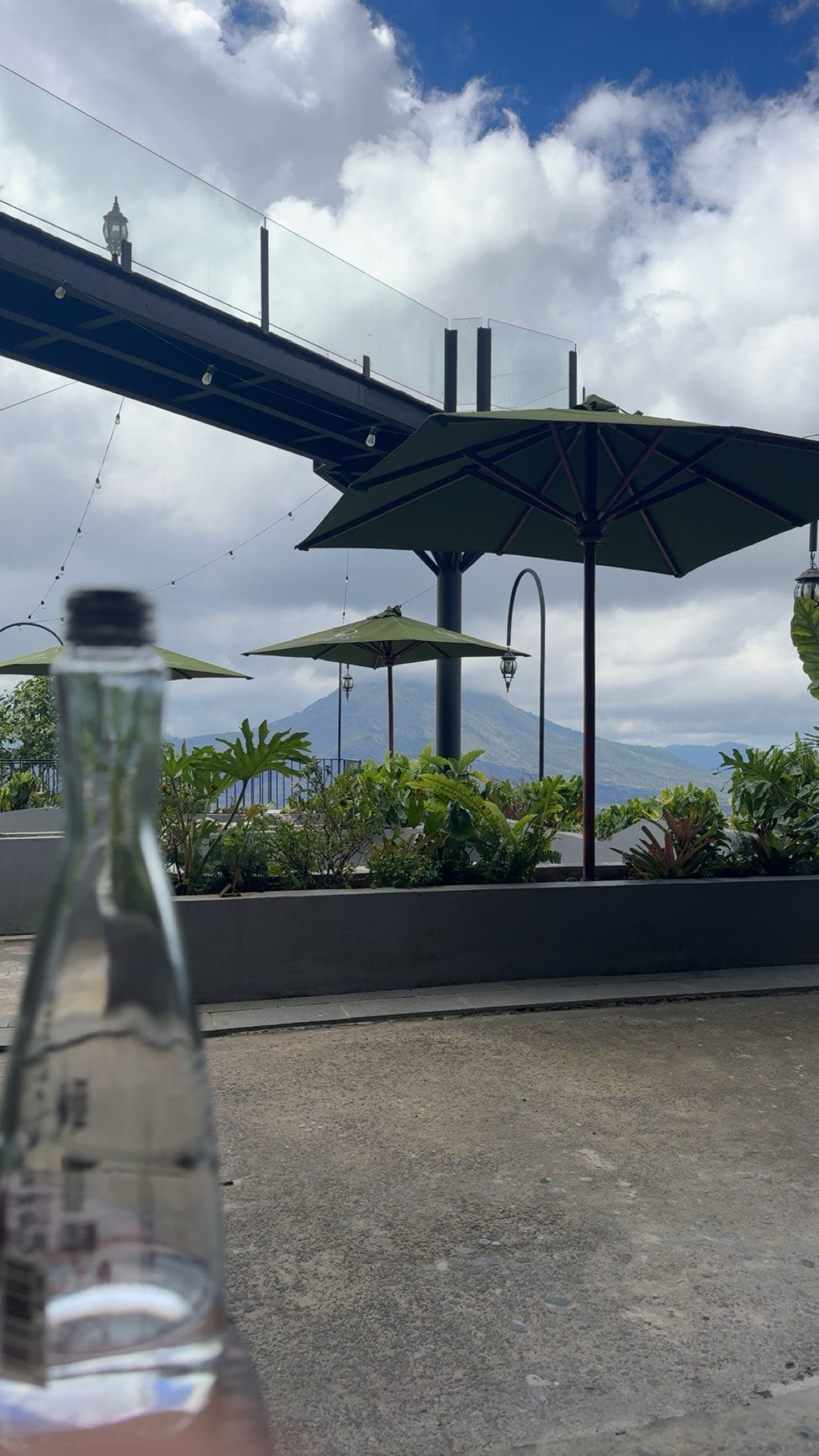 Outdoor restaurant terrace in Kintamani with umbrellas and Mount Batur caldera view.